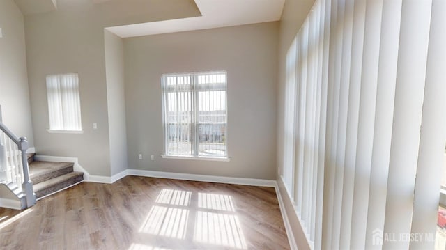 spare room featuring stairway, baseboards, and wood finished floors