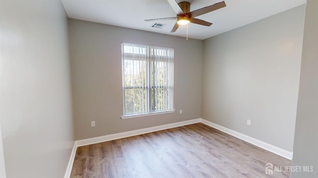 spare room with visible vents, baseboards, wood finished floors, and a ceiling fan