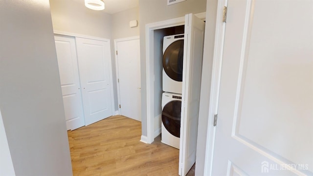 laundry area with light wood-type flooring, stacked washer and dryer, and laundry area