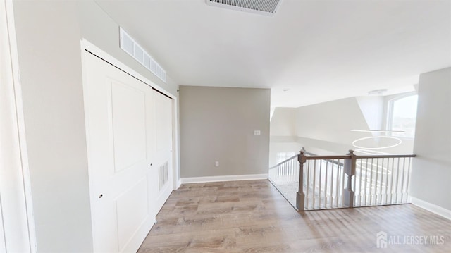 hallway with visible vents, baseboards, and wood finished floors