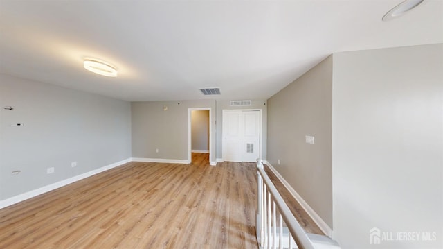 empty room featuring light wood-style flooring, baseboards, and visible vents