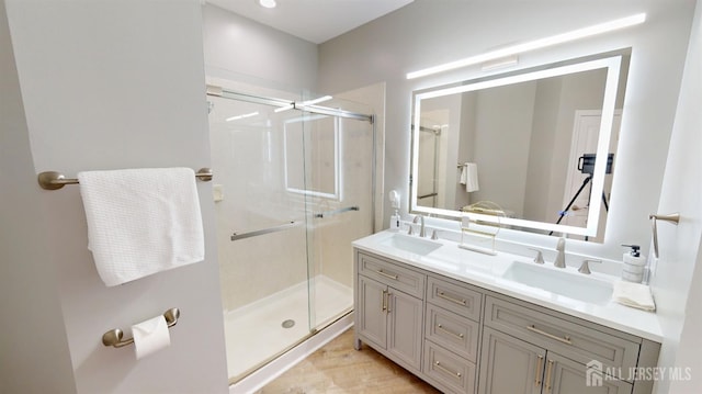 bathroom featuring a sink, a stall shower, and double vanity