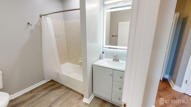 bathroom with toilet, shower / bath combo, wood finished floors, baseboards, and vanity