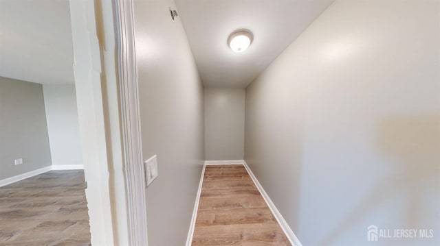 corridor featuring baseboards and wood finished floors