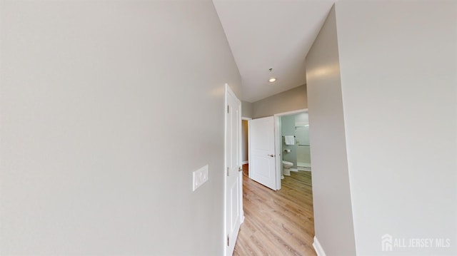 hallway with recessed lighting, light wood-type flooring, lofted ceiling, and baseboards