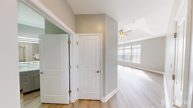 corridor featuring light wood-type flooring and baseboards