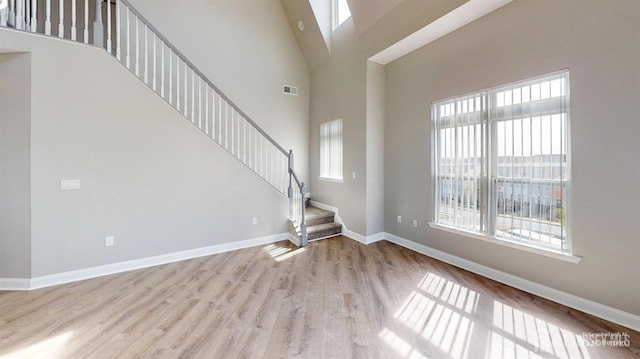 unfurnished living room with plenty of natural light, wood finished floors, visible vents, and baseboards