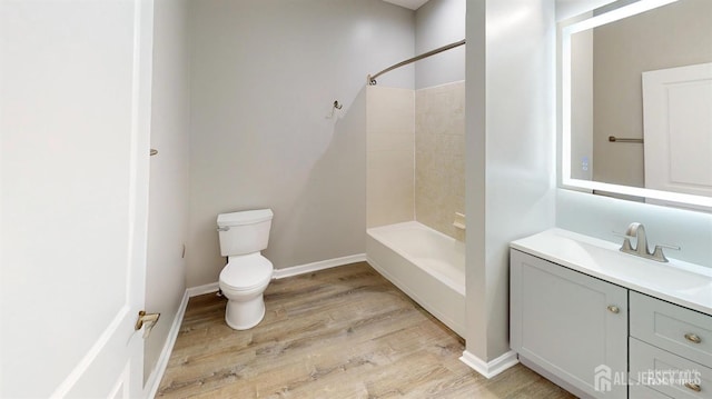 bathroom with baseboards, toilet, shower / bathing tub combination, wood finished floors, and vanity