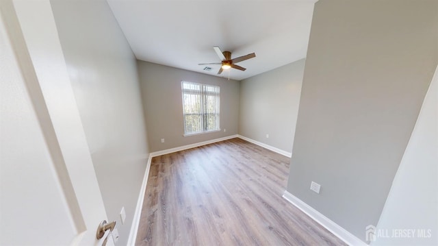 spare room with visible vents, ceiling fan, baseboards, and wood finished floors