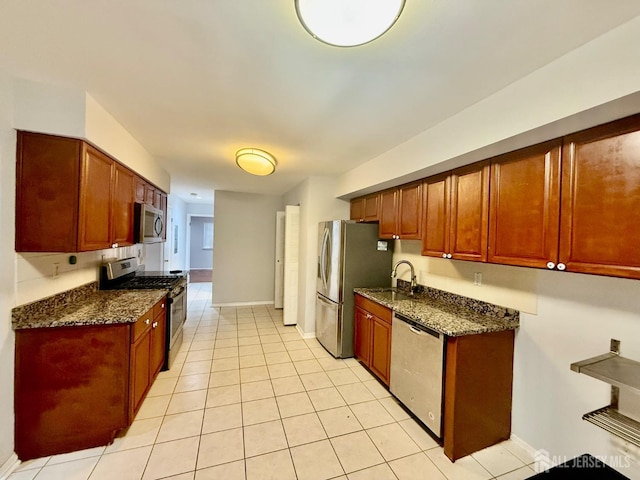 kitchen featuring dark stone countertops, baseboards, appliances with stainless steel finishes, and light tile patterned floors