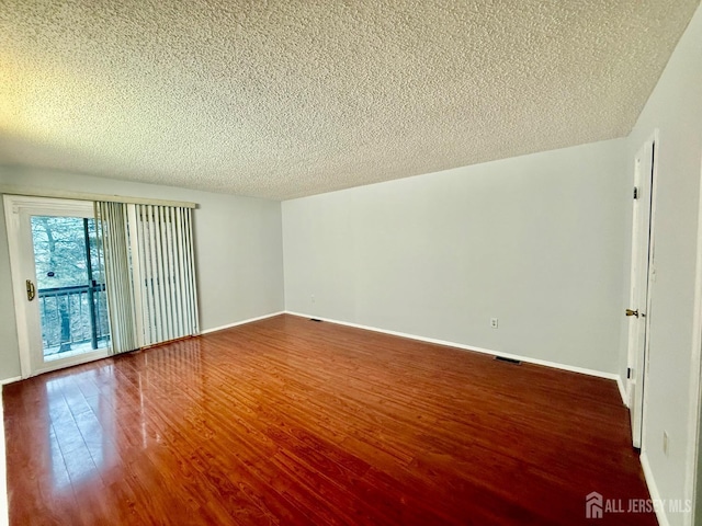 spare room with a textured ceiling and dark hardwood / wood-style flooring