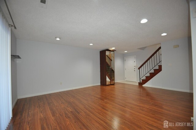 unfurnished living room with dark hardwood / wood-style flooring and a textured ceiling