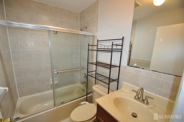 full bathroom with vanity, shower / bath combination with glass door, and toilet