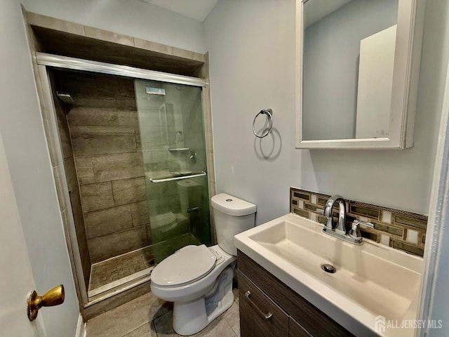 bathroom featuring tile patterned flooring, tasteful backsplash, toilet, a shower with door, and vanity