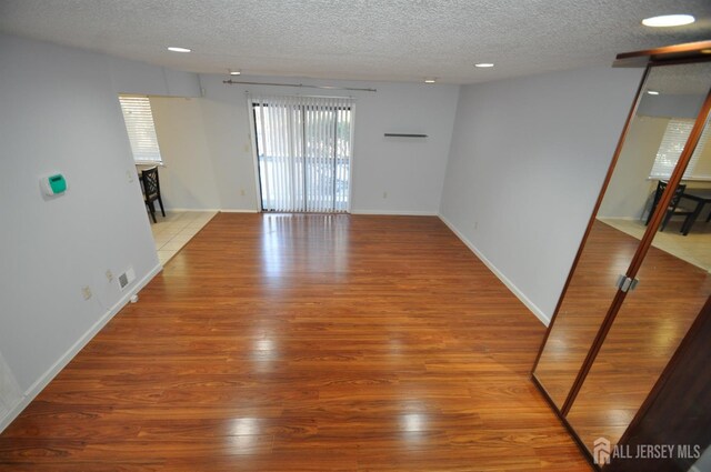 unfurnished living room with a textured ceiling and light wood-type flooring