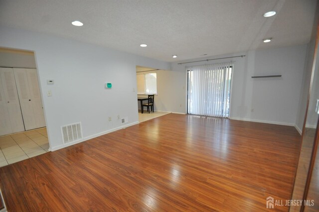 spare room with a textured ceiling and light hardwood / wood-style floors