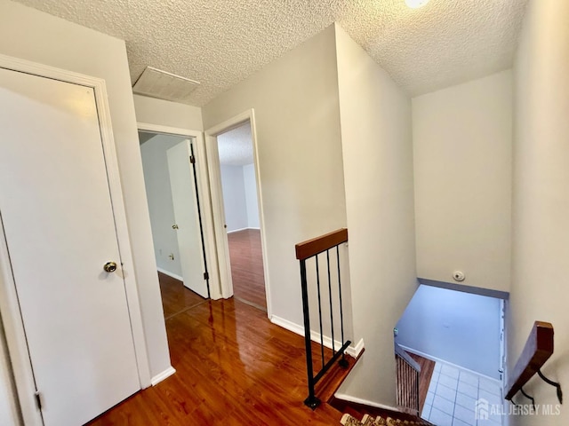 corridor with dark hardwood / wood-style flooring and a textured ceiling