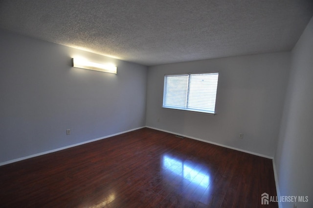 unfurnished room with dark hardwood / wood-style flooring and a textured ceiling