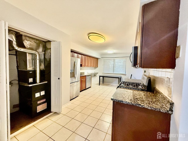 kitchen with dark stone countertops, tasteful backsplash, stainless steel appliances, and light tile patterned floors