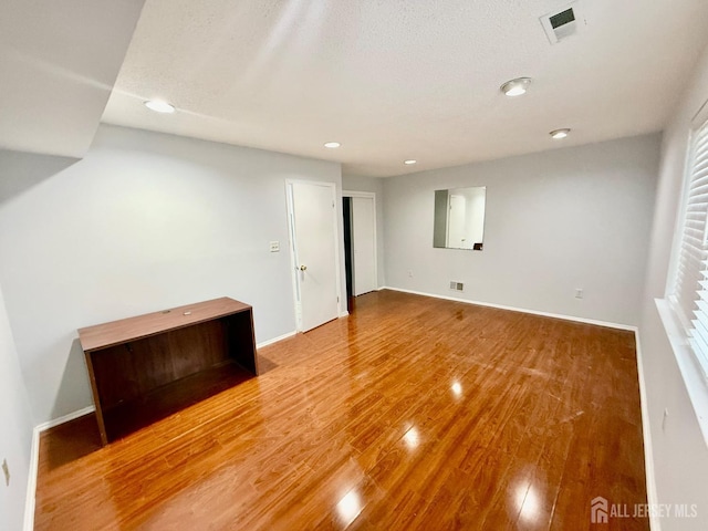 spare room featuring a textured ceiling and hardwood / wood-style floors