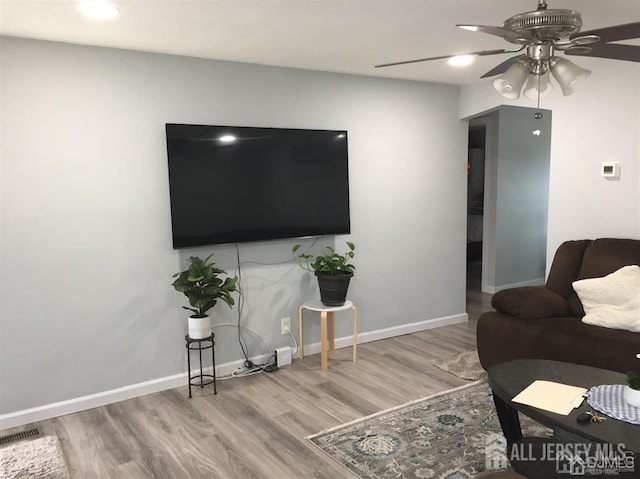 living room featuring visible vents, ceiling fan, baseboards, and wood finished floors