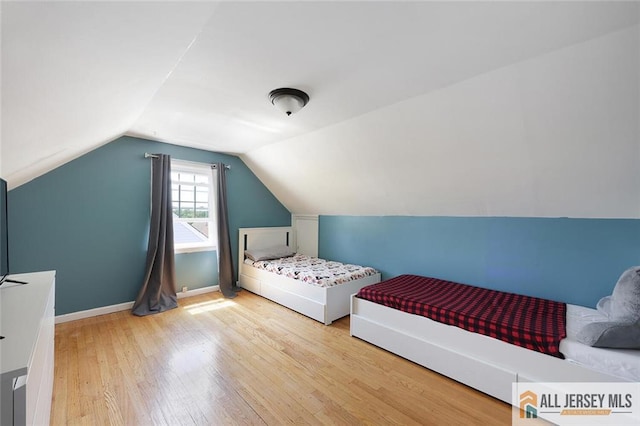 bedroom featuring wood finished floors, lofted ceiling, and baseboards