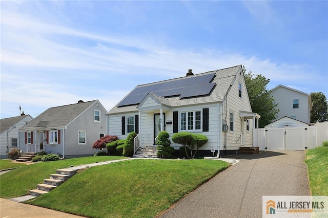 75 Strawberry Hill Ave, Woodbridge Proper, NJ 07095 - view of front facade featuring a gate, roof mounted solar panels, a shingled roof, and a chimney