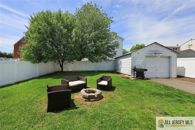 view of yard featuring a fire pit, driveway, an outbuilding, and a garage