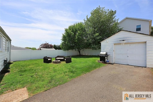 view of yard with an outdoor fire pit, an outbuilding, asphalt driveway, and a detached garage