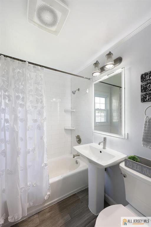 bathroom featuring toilet, shower / bath combo, wood finished floors, and ornamental molding
