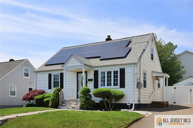 view of front of house featuring solar panels, a chimney, a gate, and roof with shingles