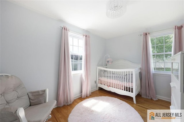 bedroom with wood finished floors and a nursery area
