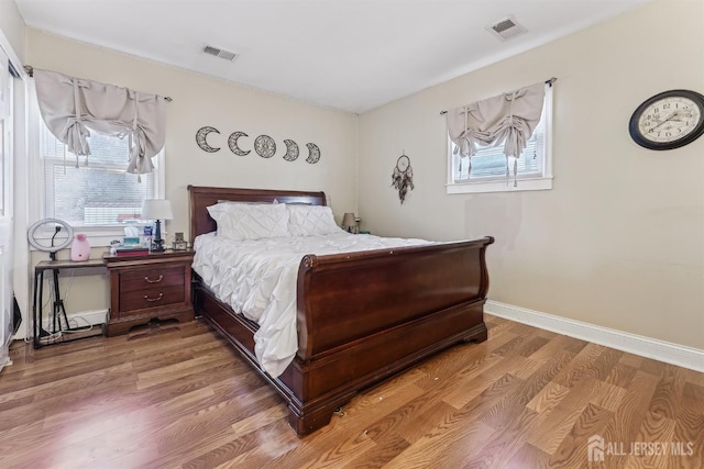 bedroom featuring light wood-type flooring, visible vents, and baseboards