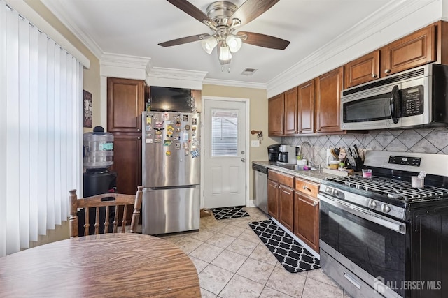 kitchen featuring ornamental molding, a sink, appliances with stainless steel finishes, light tile patterned flooring, and decorative backsplash