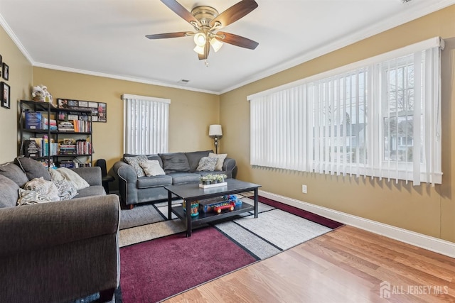 living room with ornamental molding, ceiling fan, baseboards, and wood finished floors