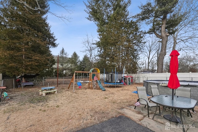 view of playground featuring a trampoline and a fenced backyard