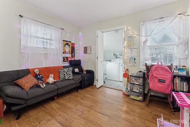 living room with washer and dryer, wood finished floors, and a healthy amount of sunlight