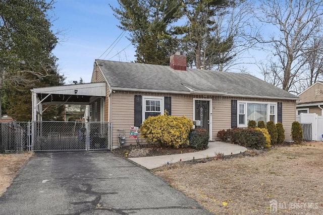 view of front facade featuring an attached carport, a gate, fence, driveway, and a chimney