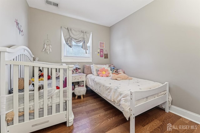 bedroom with wood finished floors, visible vents, and baseboards