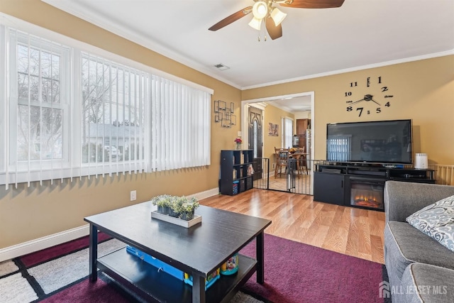 living room with visible vents, crown molding, baseboards, and wood finished floors