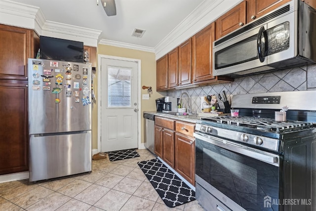 kitchen featuring visible vents, ornamental molding, a sink, tasteful backsplash, and stainless steel appliances