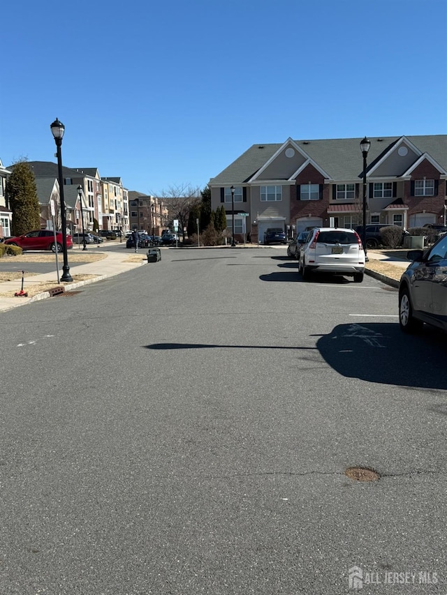 view of street with a residential view, curbs, street lighting, and sidewalks