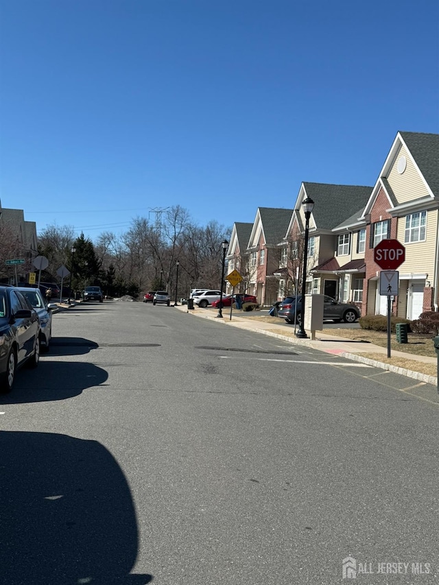 view of street featuring traffic signs, sidewalks, curbs, street lighting, and a residential view