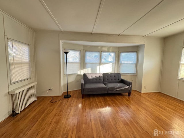 unfurnished room with radiator, baseboards, and light wood-style floors