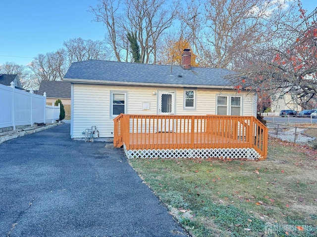 back of property with a wooden deck and a yard