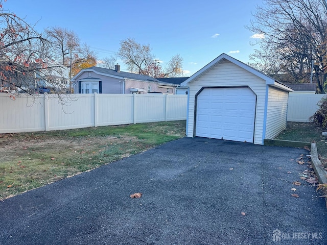 detached garage with aphalt driveway and fence