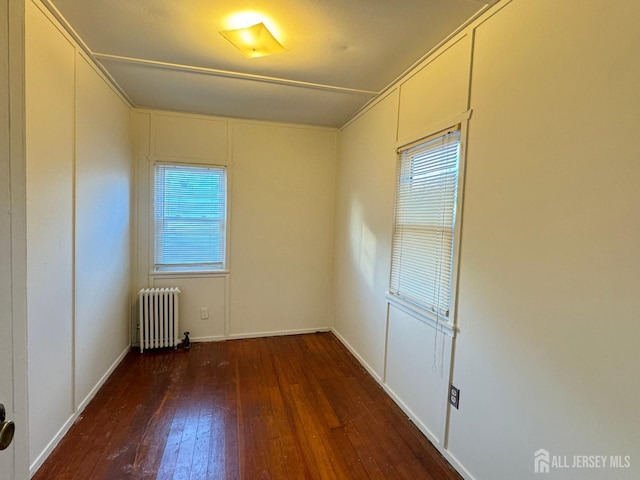 spare room featuring dark wood-type flooring and radiator heating unit