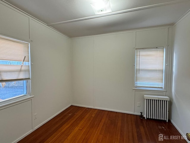 unfurnished room featuring dark wood-style floors, radiator heating unit, baseboards, and a decorative wall