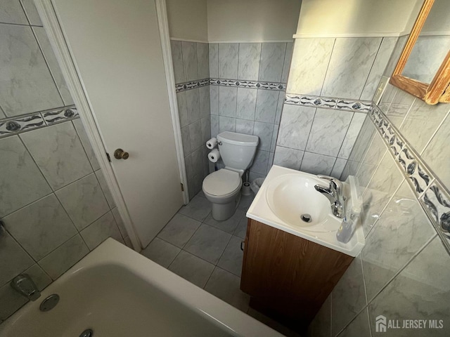 full bathroom featuring toilet, tile patterned flooring, a bathtub, vanity, and tile walls