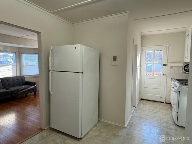 kitchen with white appliances, decorative backsplash, white cabinets, ornamental molding, and light countertops